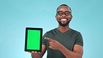 Tablet, green screen and pointing to on screen with a black man in studio on a blue background. Technology, website and chromakey on a mobile display for perfect marketing or advertising on an app