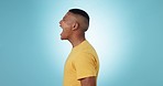 Screaming, angry and profile of a man, burnout and furious on a blue studio background. Person, guy and model shouting, stress or anxiety with emotion, expression or frustrated with crisis or problem