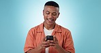 Phone, networking and young man in a studio typing a message on the internet or mobile app. Happy, smile and male model from Mexico scroll on social media with cellphone isolated by blue background.