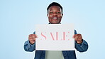 Marketing, poster and sale with a black man on a blue background in studio for retail shopping. Portrait, smile and sign for a deal, discount or bargain with a happy young person holding paper info