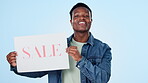 Advertising, poster and sale with a black man on a blue background in studio for retail shopping. Portrait, smile and sign for a deal, discount or bargain with a happy young person holding paper info