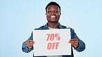 Information, poster and sale with a black man on a blue background in studio for retail shopping. Portrait, smile and sign for a deal, discount or bargain with a happy young person holding paper news