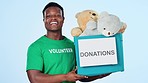 Happy, black man and a box for donation with a volunteer with toys or a teddy on a studio background. Smile, face portrait and an African volunteering worker with a gift or present for charity