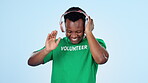 Music, dance and smile with a black man volunteer on a blue background in studio for freedom or charity. Community, energy and a happy young person streaming audio with headphones for welfare