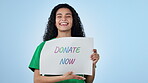 Donate, poster and smile with a woman volunteer on a blue background in studio for community service. Portrait, paper and charity with a happy young person showing a sign for welfare donation