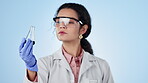 Women, scientist and glass beaker for analysis, studio and experiment with liquid, chemistry and chemicals. Science, biotechnology and blue background for thinking, safety wear and virus testing
