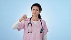Nurse, woman and thumbs down, review and decision with reaction to healthcare, disagreement and hand gesture on blue background. Portrait, medical opinion and negative feedback on surgery in studio