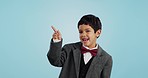 Pointing, face or happy child in studio for offer, discount deal or retail sale on mockup space or logo advertising. Business, funny or excited boy with smile, news or kids promo on blue background