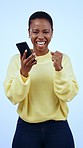 African woman, phone and celebration in studio for trading success, profit or goals by blue background. Excited winner girl, smartphone and fist for cheers, prize or lotto with revenue, money or loan