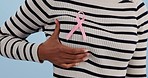 Ribbon, closeup and woman with cancer awareness, support and health on a blue studio background. Zoom, person and girl with solidarity, campaign and hope with gratitude, insurance cover and chest