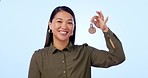 Happy asian woman, keys and real estate for property, investment or homeowner against a studio background. Portrait of female person showing key ring for mortgage loan, apartment or buying new house