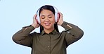 Music, headphones and woman dance in studio happy with radio or audio track on blue background. Podcast, earphones and asian female model with feel good album, subscription or dancing playlist vibes