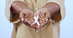 Breast cancer, organisation and ribbon with hands, woman and together for awareness, help and support. Closeup, community and solidarity for medical, diagnosis and health in blue studio background