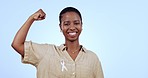 Woman, breast cancer ribbon and smile in studio with strong arm sign, resilience and motivation by blue background. Happy African person, muscle and face for health, wellness or survival from disease