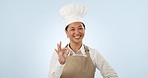 Woman, chef and face with ok hand sign of coffee shop owner ready for cooking in studio. Female person, restaurant worker and baker confidence with yes emoji and perfect gesture with blue background