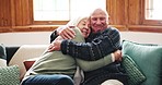 Love, face and senior couple hug on a sofa with support, care and trust in their home together. Happy, portrait and old people embrace in a living room bonding, relax and enjoy retirement together