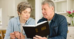 Reading, bible and Christian senior couple with spiritual faith in holy book together in home living room as worship. Retirement, religion and elderly people learning about God or text for faith