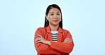 Portrait, arms crossed and attitude with a negative asian woman in studio on a blue background. Rejection, deny or no with an annoyed young person looking moody or unimpressed by a mistake or problem