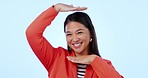 Face, hands and frame for photography with an asian woman in studio to measure on a blue background. Portrait, smile and social media with a happy young person posing for a profile picture update