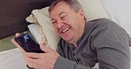 Phone, laughing and senior man in bed watching funny, comic or comedy video on the internet. Happy, technology and elderly male person in retirement scroll on social media with cellphone at home.