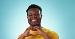 Happy, face and a black man with heart hands on a blue background for care, support and flirting. Smile, wink and portrait of an African person with a gesture for love, kindness and gratitude