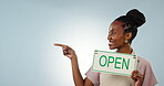 Space, pointing and open sign with a happy black woman in studio on a gray background for advertising. Portrait, smile and coffee shop with a happy young employee showing mockup for marketing