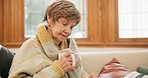 Coffee, bible and senior woman on sofa in home for religion, spiritual learning and faith. Christianity, retirement and elderly person reading holy book for studying, relax and worship in living room