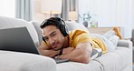 Man on couch with laptop, headphones and movie on social media, video streaming or network website. Relax, internet and happy person on sofa with computer, earphones and watching film audio on app.