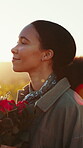 Face, flowers and thinking with a black woman at sunset, looking happy outdoor in nature for romance. Smile, spring and rose bouquet with a happy young person in the countryside on valentines day