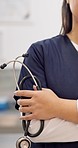 Woman, hand and stethoscope of professional doctor with arms crossed in healthcare or medical service at hospital. Closeup of female person or nurse in confidence with tools or equipment for health