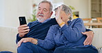 Senior, wave and couple with phone for video call on sofa with hug, communication and happiness in living room. Elderly, man and woman with smartphone on couch with greeting online for conversation