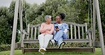 Senior, woman and nurse with phone in garden with communication for memory loss, dementia or alzheimer. Elderly, black people and caregiver with smartphone on swing with pictures to remember or doubt