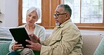 Senior couple, tablet and talking on sofa for reading news app, social media post or ebook at home. Old man, woman and interracial partner scroll on digital blog, online shopping or web in retirement