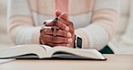 Hands, praying and Bible, cross for worship and God, Christian at home with closeup of prayer and study scripture. Religion, wellness and person has crucifix, faith and search for guidance with trust