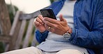 Closeup, outdoor and senior man with a smartphone, typing and internet with social media, texting and message. Mature person, pensioner on a bench and guy with a cellphone, contact and website info