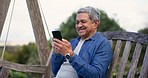 Happy, outdoor and senior man with a cellphone, typing and internet with social media, contact and message. Mature person, pensioner on a bench and mature guy with a smartphone, network and happiness