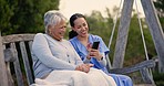 Senior woman, nurse and outdoor with phone, laugh and funny video on swing chair, relax and reading chat. Caregiver, elderly person and smartphone for comedy, memory or notification at nursing home