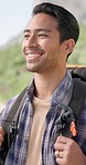 Hiking, nature and Asian man on mountain with backpack for adventure, trekking and freedom. Travel, fitness and happy person smile outdoors walking for wellness, vacation and exercise on holiday