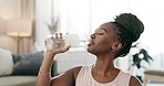 Exercise, black woman and drinking water in bottle in home, healthy diet or wellness. African athlete, thirsty or liquid for hydration after workout, sport training or fitness to relax in living room