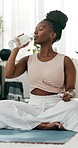 Drinking water, yoga or black woman in home with wellness, fitness or health for hydration after exercise. Thirsty African person, living room or healthy lady with liquid after training to relax