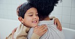 Happy, love and mother hugging her child in bathtub for care and bonding together at home. Smile, bathroom and face of young boy kid embracing his mom and kissing cheek on a weekend at modern house.