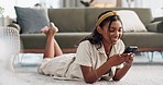 Phone, relax and happy woman on a floor with social media, chat or text in her home. Smartphone, app and Indian lady person lying in living room with online dating, search or funny gif communication