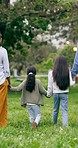 Walking, holding hands and family in park, bonding in nature with freedom and support from back. Mom, dad and kids in garden with trees, grass and natural outdoor love in green countryside together.