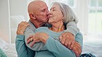 Senior couple, hug and kiss in bedroom, care and conversation together at home. Love, elderly man and happy woman in bed, embrace and connection for support, relationship and commitment to marriage