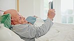 Senior couple lying in bed with tablet, video and checking social media, post and relax in home together. Digital app, old man and woman in bedroom reading email, website or online love in marriage.