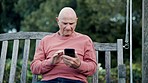 Elderly, man and outdoor with phone on bench for social media, mobile app or reading of message. Senior citizen, technology and scrolling for news, announcement and notification on web by internet