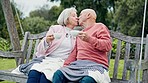 Senior couple on swing in garden with kiss, coffee and conversation, bonding with support and care. Relax, old man and woman in backyard together, talking and love with happy marriage in retirement