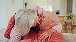 Senior couple, kiss and home with hug, love and care together in retirement with marriage. Lounge, smile and relax with a woman and calm man together with support in a living room with embrace