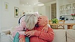 Senior couple, kiss and home with love, support and care together in retirement with marriage. Lounge, smile and relax with a woman and calm man together with rest in a living room with embrace