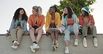 Happy woman, friends and laughing at park for funny joke, meme or gossip while sitting on wall. Group of female people, smile and laugh in joy together for outdoor fun, social or get together outside